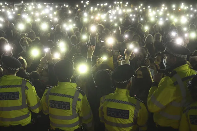 People gather and turn on their phone torches in Clapham Common, despite the Reclaim These Streets vigil for Sarah Everard being officially cancelled, in London, Saturday, March 13, 2021. (Photo by Victoria Jones/PA Wire via AP Photo)