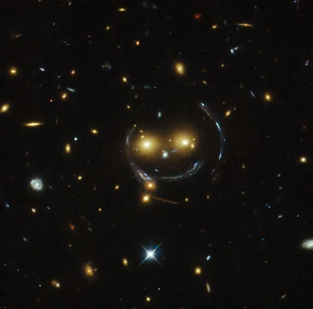 The galaxy cluster SDSS J1038+4849 is pictured in this undated handout image taken with the NASA/ESA Hubble Space Telescope. As a result of the phenomenon of gravitational lensing, it seems to be smiling. In the case of this “happy face”, the two eyes are very bright galaxies and the smile lines are actually arcs caused by strong gravitational lensing. 
(Photo by Reuters/NASA)