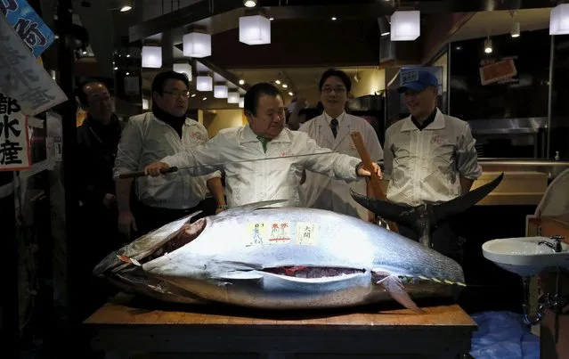 Kiyomura Co's President Kiyoshi Kimura (C), who runs a chain of sushi restaurants, holds a sword as he poses with a 200 kg (400 lbs) bluefin tuna at his sushi restaurant outside Tsukiji fish market in Tokyo, Japan, January 5, 2016. (Photo by Toru Hanai/Reuters)