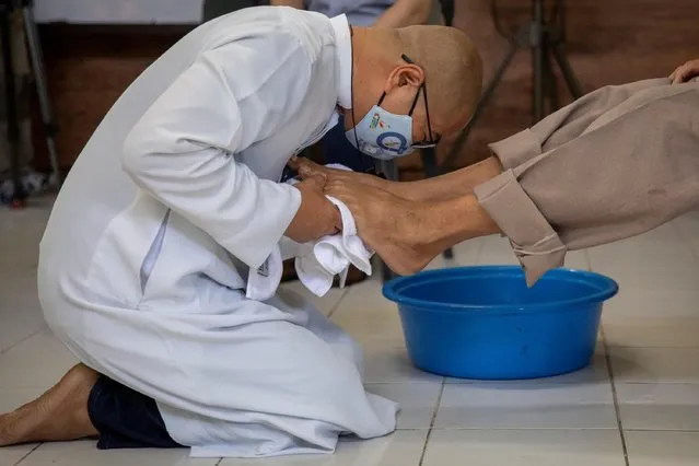 Flavie Villanueva, a Catholic priest from the Society of the Divine Word, wearing a face mask amid the coronavirus disease (COVID-19) pandemic, leans to kiss the feet of a homeless man after washing them on Maundy Thursday in Manila, Philippines, April 1, 2021. (Photo by Eloisa Lopez/Reuters)