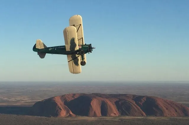 British aviator Tracey Curtis-Taylor pilots her biplane past Australia's Uluru rock formation during her historic England-to-Australia journey, in this handout picture taken January 6, 2016. Curtis-Taylor arrived in Australia's largest city on Saturday, three months after setting off from England to retrace a pioneering feat of early aviation. (Photo by Reuters)