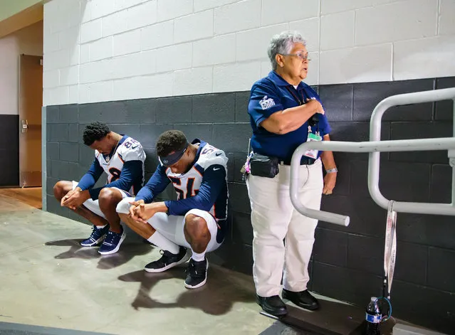 A stadium security guard stands with her hand over her heart as Denver Broncos linebacker Brandon Marshall (54) and wide receiver Demaryius Thomas (88) sit in silent protest during the national anthem prior to the game against the Arizona Cardinals during a pre season game at University of Phoenix Stadium in Glendale, AZ, USA on August 30, 2018. (Photo by Mark J. Rebilas/USA TODAY Sports via Reuters)