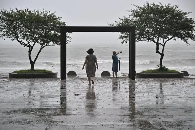 A man takes a selfie in front of the beach in the southeastern port city of Busan on August 10, 2023, as Typhoon Khanun approaches. Airlines cancelled several hundred flights and authorities issued warnings August 9, 2023 as tropical storm Khanun barrelled off Japan's southern coast towards South Korea. The storm, which has been downgraded from typhoon status, has already prompted South Korea to begin the evacuation of tens of thousands camping at the World Scout Jamboree, which was earlier hit by a heatwave. (Photo by Anthony Wallace/AFP Photo)