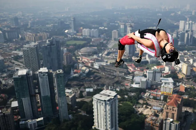 Base jumpers leap from the 300-metre high skydeck of Malaysia's landmark Kuala Lumpur Tower against the backdrop of the city's skyline in Kuala Lumpur on September 30, 2018 during the annual International KL Tower Base-Jump event. (Photo by Manan Vatsyayana/AFP Photo)