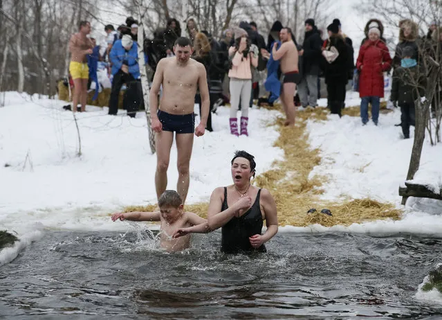 People react as they take a dip in a lake during Orthodox Epiphany celebrations in Kiev, Ukraine, January 19, 2016. Orthodox Christians celebrate the religious holiday of Epiphany according to the Gregorian calendar on January 19 by immersing themselves in water. (Photo by Gleb Garanich/Reuters)