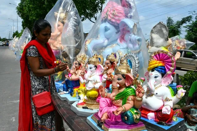 A woman paints clay idols of Hindu deity Ganesha along a street, as she waits for customers ahead of the Ganesh Chaturthi festival in Hyderabad on September 16, 2023. (Photo by Noah Seelam/AFP Photo)