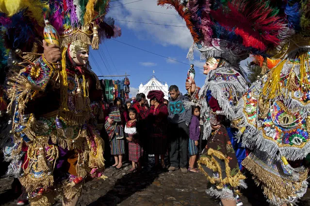 Masked dancers perform outside St. Thomas church during a celebration honoring the patron saint of Chichicastenango, Guatemala, Wednesday, December 21, 2016. The church is built atop a former temple and incorporates the temple's 18 steps, each representing a month of the Mayan calendar. (Photo by Moises Castillo/AP Photo)