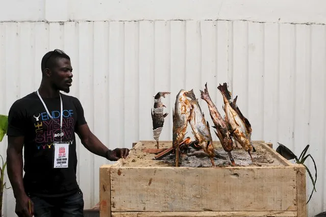 A vendor grills fish during the attieke and fish festival in Abidjan, Ivory Coast, January 30, 2016. (Photo by Joe Penney/Reuters)