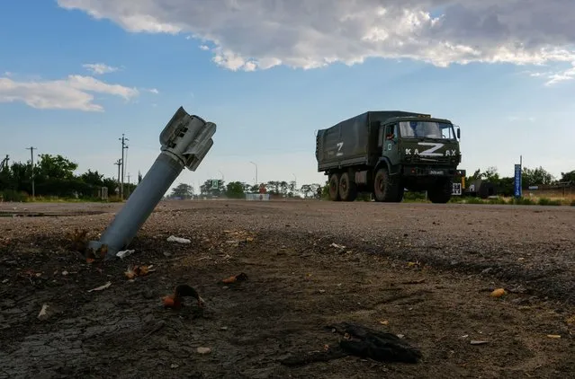 A Russian military truck drives past an unexploded munition during Ukraine-Russia conflict in the Russia-controlled village of Chornobaivka, Ukraine on July 26, 2022. (Photo by Alexander Ermochenko/Reuters)