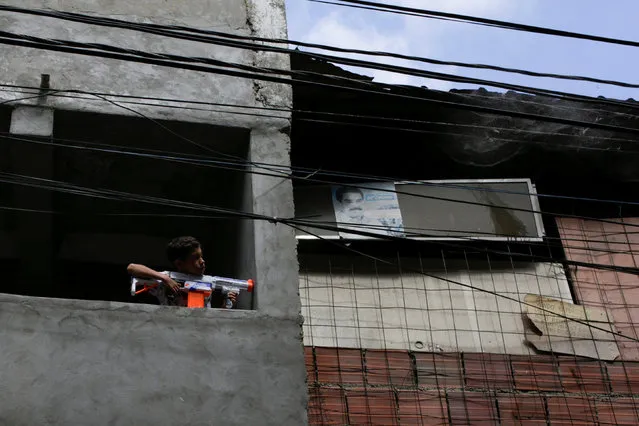 A boy plays with a toy gun at the slum of Petare in Caracas, Venezuela December 20, 2016. (Photo by Marco Bello/Reuters)