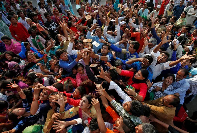 People raise their hands to collect money distributed by a Muslim man during a procession to celebrate the festival of Eid-e-Milad-ul-Nabi, the birth anniversary of prophet Mohammad, in Ahmedabad, India, November 21, 2018. (Photo by Amit Dave/Reuters)