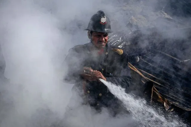 A firefighter tries to extinguish a fire in a slum area in Mumbai, on November 21, 2013. Several huts were gutted in the fire but no casualties were reported and the cause is unknown. (Photo by Danish Siddiqui/Reuters)