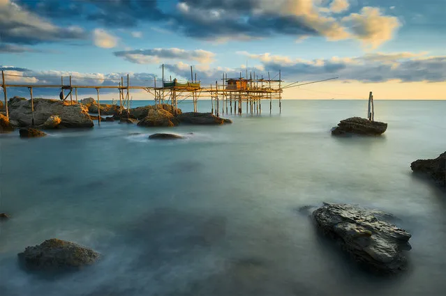 “A violent september sunrise”. A trabocco is an old fishing machine built from wood jutting out into the sea, from where two (or more) long arms called antemna stretch out suspended some feet above the water and supporting a huge net. Photo location: San Vito Chietino, Abruzzo, Italy. (Photo and caption by Giacomo Ciangottini/National Geographic Photo Contest)