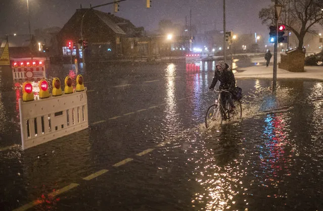 In this Thursday, January 4, 2017 photo a woman rides her bicycle through flooding in Wismar, northern Germany, after the northern German coast region was hit by high tide. (Photo by Jens Buettner/DPA via AP Photo)