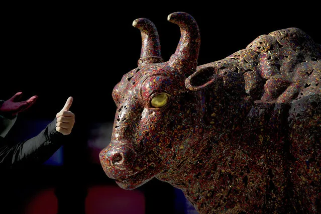Chinese people gesture as they pose for photograph near a bull sculpture titled “Five Bulls Gathering Fortune” on display at the Wangfujing shopping district in Beijing, Thursday, January 10, 2019. Uncertainty over the outcome of China-U.S. trade talks is casting a pall over Asian markets as both sides kept quiet about what lies ahead. (Photo by Andy Wong/AP Photo)