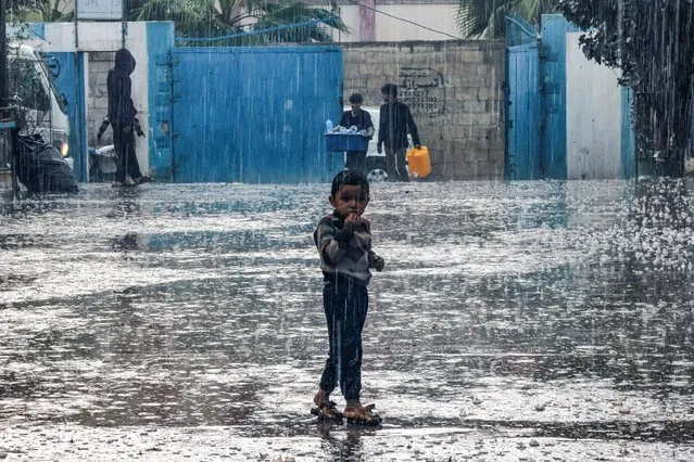 A boy stands in the rain at a school run by the United Nations Relief and Works Agency for Palestine Refugees in the Near East (UNRWA) in Rafah in the southern Gaza Strip on November 14, 2023, where internally displaced Palestinians have taken refuge amid ongoing battles between Israel and the Palestinian militant group Hamas. (Photo by Said Khatib/AFP Photo)
