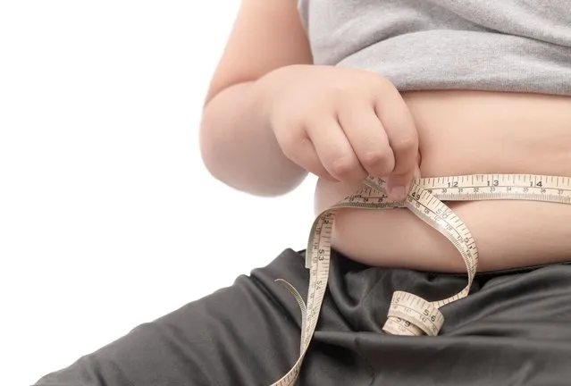 Fat child check out his body fat with measuring tape isolated on white background, obesity or diet concept. (Photo by kwanchaichaiudom/Getty Images)