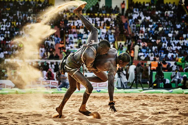 “The Gris-gris Wrestlers of Senegal”. Sports, second prize stories. Christian Bobst, Switzerland. Kherou, a young wrestling champion, performs a ritual in the water of the sea while pouring milk over his body in order to obtain the reinforcement of a ghost who lives in the stones at the shore, August 11, 2015. Wrestlers performing rituals in Senegal. These tournaments resemble a festival including dance performances, music, and wrestling shows. (Photo by Christian Bobst/World Press Photo Contest)