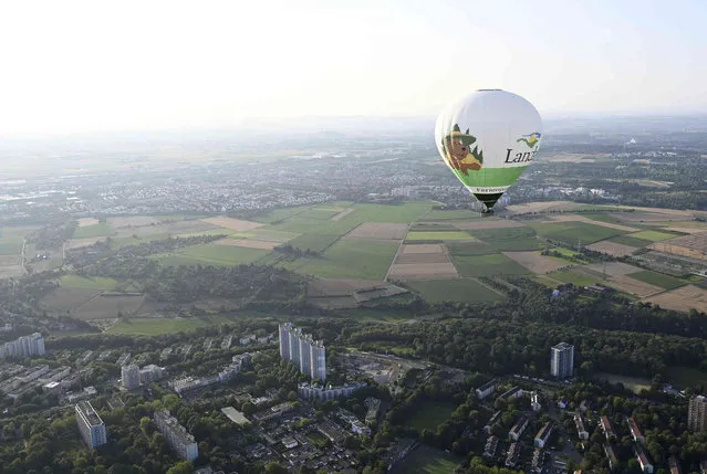According to the manufacturer, the largest hot air balloon ever produced in Germany floats over Stuttgart, Germany, on its maiden flight, Wednesday, July 21, 2021. According to the information, the green-white record balloon has a volume of 12,500 cubic meters. (Photo by Bernd Wei'brod/dpa via AP Photo)