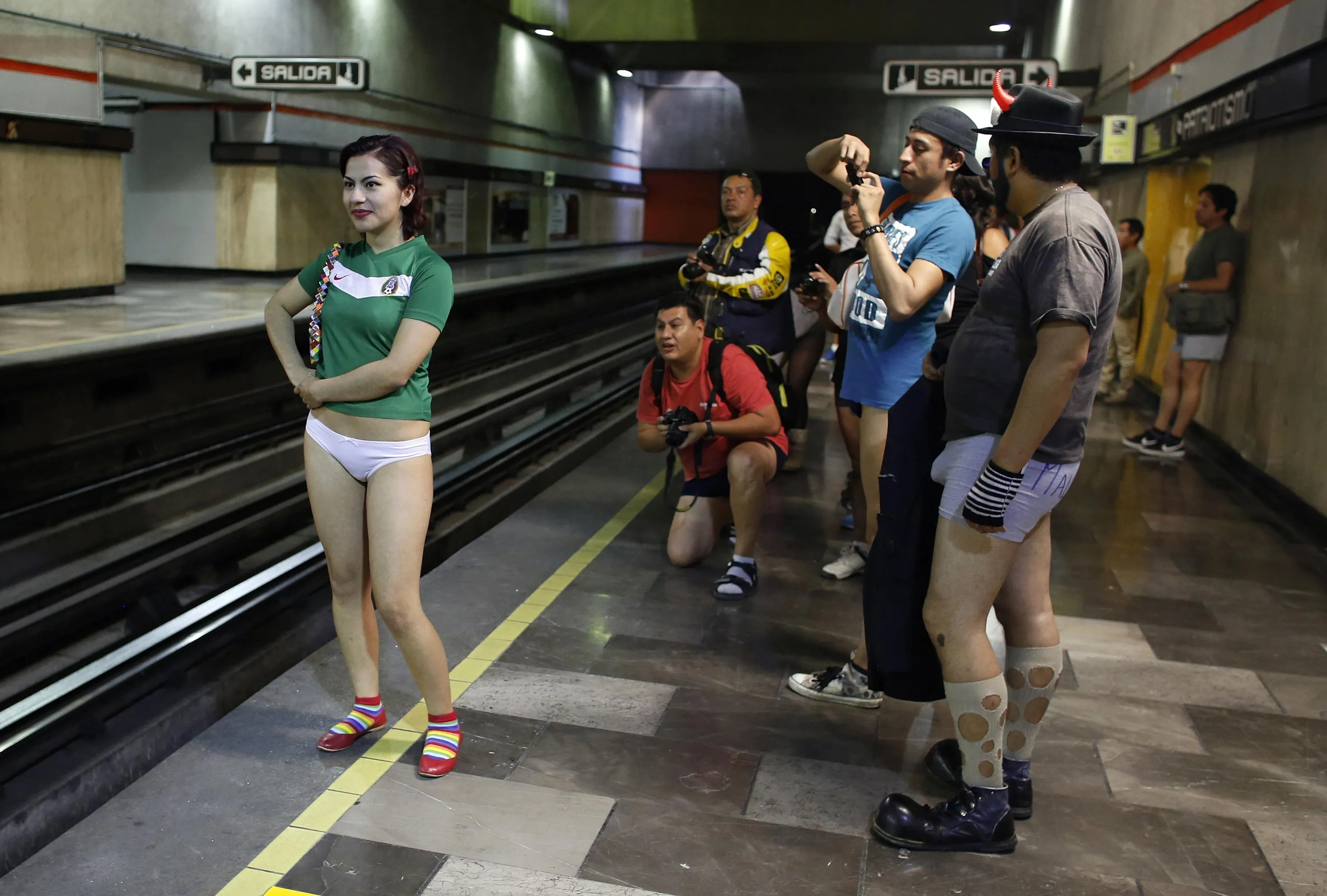 A woman without pants is photographed by members of her team at an undergro...