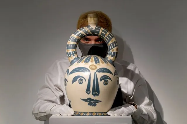 An art handler displays a ceramic vase by Pablo Picasso called “Vase Azteque Aux Quatre Visages” at Christie's auction rooms in London, Friday, September 17, 2021. The vase estimated at 55,000-75,000 UK Pounds (75,900-102,900 US Dollars) will be up for auction in the Christie's Sept. online only sales. (Photo by Kirsty Wigglesworth/AP Photo)