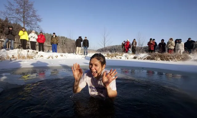 A woman reacts after dipping herself into the icy waters of a lake near the village of Zadomlia, some 40 km (25 miles) east of Minsk, January 19, 2014. Orthodox believers marked Epiphany on January 19 by immersing themselves in icy waters regardless of the weather. (Photo by Vasily Fedosenko/Reuters)