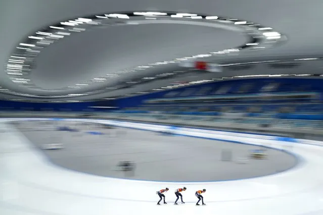 In this photo taken with a long shutter speed, members of the Netherlands team compete in the men's pursuit during the Speed Skating China Open, a test event for the 2022 Winter Olympics, at the National Speed Skating Oval in Beijing, Saturday, October 9, 2021. (Photo by Mark Schiefelbein/AP Photo)
