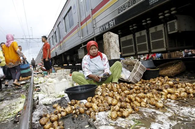 A woman peels potatoes for sale at a market located along a railway line in West Jakarta, Indonesia March 1, 2016. (Photo by Garry Lotulung/Reuters)