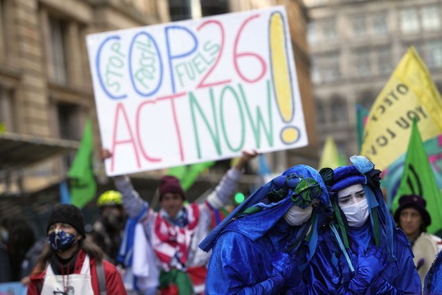 Extension Rebellion activists protest outside JP Morgan premises as they take part in a demonstration against “Greenwashing” (an attempt to make people believe that your company or government is doing more to protect the environment than it really is) near the COP26 U.N. Climate Summit in Glasgow, Scotland, Wednesday, November 3, 2021. (Photo by Alastair Grant/AP Photo)