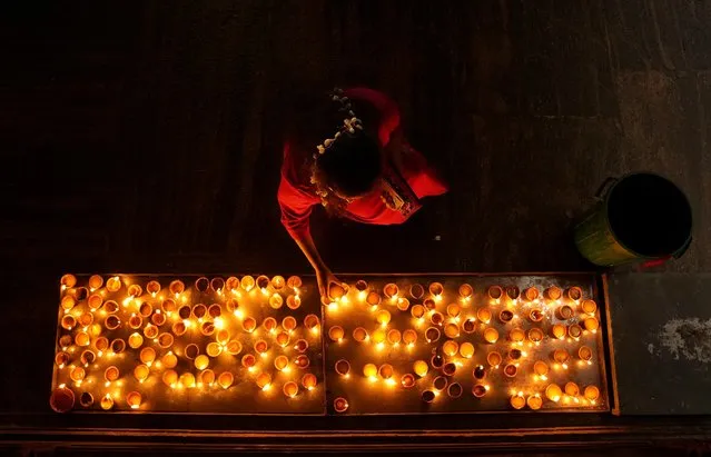 An ethnic Tamil woman prays holding a tray of oil lamps during Diwali, the Hindu festival of lights, in Colombo, Sri Lanka, Thursday, November 4, 2021. Millions of people across Asia are celebrating the Hindu festival of Diwali, which symbolizes new beginnings and the triumph of good over evil and light over darkness. (Photo by Eranga Jayawardena/AP Photo)