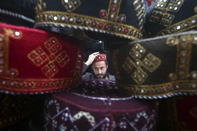 A man tries on a traditional cap which will be used while praying during the Muslim fasting month of Ramadan, at a stall in Peshawar, Pakistan, Monday, March 11, 2024. (Photo by Muhammad Sajjad/AP Photo)