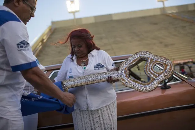 Maria Cristina de Jesus, the guardian of Rio's city key, places the oversized key in a bag during a delay for the ceremony officially kicking off Carnival at the Sambadrome in Rio de Janeiro, Brazil, Friday, February 24, 2017. De Jesus' late father, Jose Geraldo de Jesus, also known as Candonga, kept the key safe at his home after it kept getting lost year after year since the 1970's. After his death in 1997, his family kept up the tradition of keeping the key safe at their home. (Photo by Mauro Pimentel/AP Photo)