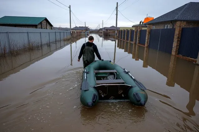A man tows an inflatable boat along a flooded street in in the settlement of Ivanovskoye, Orenburg region, Russia on April 10, 2024. (Photo by Maxim Shemetov/Reuters)