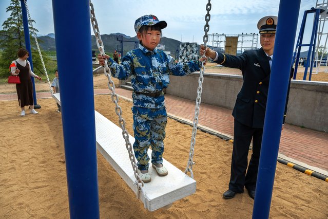 A Chinese naval officer plays with is child on equipment used in an obstacle course as part of an open house at the PLA Navys Submarine Academy as part of events marking the 75th Anniversary of the founding of the countrys navy on April 21, 2024 in Qingdao, China. China is hosting the Western Pacific Naval Symposium this week. (Photo by Kevin Frayer/Getty Images)