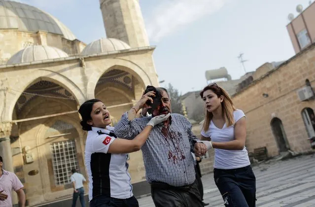 Rescue workers help a injured man after a rocket hit a mosque on April 24, 2016 in Kilis. Two rockets fired into Turkey from an area of Syria controlled by the Islamic State group hit the border town of Kilis on Sunday, leaving 16 people injured, media reports said. (Photo by Yasin Akgul/AFP Photo)