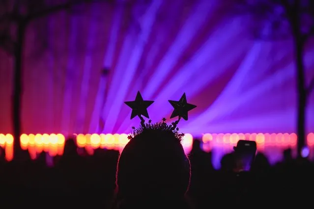 A woman watches a laser show during New Year's celebrations in Bucharest, Romania, Saturday, January 1, 2022. Thousands gathered by a lake to attend a concert and watch fireworks and a laser show during New Years celebrations in the Romanian capital. (Photo by Vadim Ghirda/AP Photo)