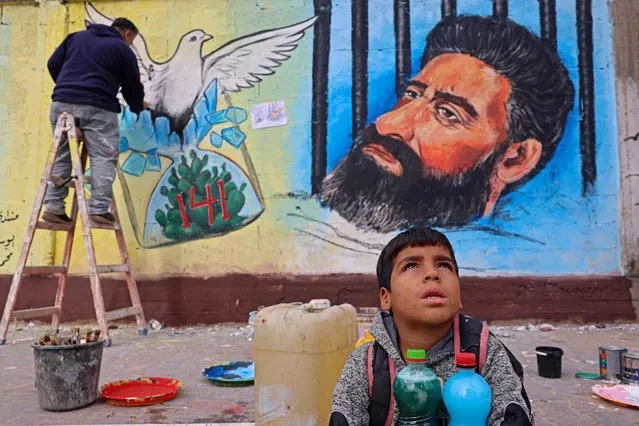 A Palestinian artist draws a mural of Hisham Abu Hawash, a Palestinian prisoner who ended his hunger strike after Israel committed to his eventual release, in Gaza City on January 5, 2022. Abu Hawash, a 40-year-old member of the Islamic Jihad militant movement, began refusing food in August to protest Israel holding him without charges or trial. (Photo by Mohammed Abed/AFP Photo)