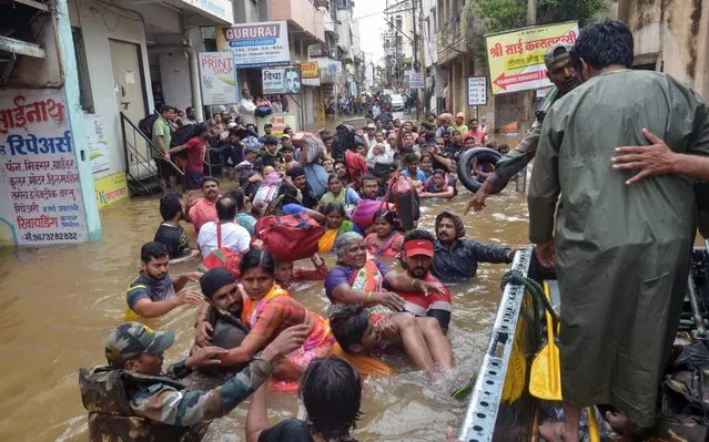 In this photograph taken on August 8, 2019, Indian Army personnel rescue people stranded in flood waters after heavy rains on the outskirts of Sangli in Maharashtra state. Parts of Maharashtra, Karnataka and Kerala are suffering one of the worst floods in recent years after heavy monsoon rains. (Photo by Uday Deolekar/AFP Photo)