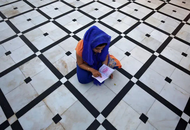 A Hindu woman reads a religious scripture as she prays inside a temple during Navratri festival in Jammu March 29, 2017. (Photo by Mukesh Gupta/Reuters)