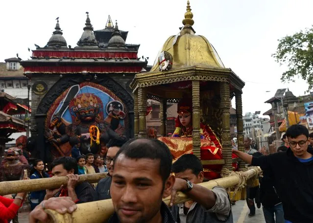 Nepal's the Living Goddess, the Kumari, is carried through a crowd during the Ghode Jatra (Horse Race) Festival in Kathmandu on March 27, 2017. The Kumari is worshipped by both Hindus and Buddhists as a living goddess and a protector bringing good luck and prosperity. (Photo by Prakash Mathema/AFP Photo)
