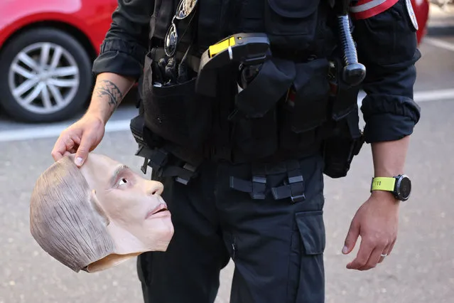 A Swiss police officer holds a mask of the Russian President after a protester has been arrested ahead of a Russia – US meeting in Geneva on June 16, 2021. (Photo by Pierre Albouy/AFP Photo)