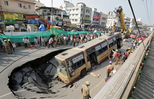 Rescue workers prepare to lift a passenger bus from a pit after a road caved in, in Chennai, India, April 9, 2017. (Photo by Reuters/Stringer)