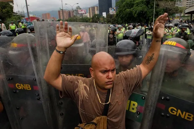 An opposition demonstrator calls on other demonstrators for calm in front members of the Venezuelan Bolivarian Army Forces during a demonstration at the Francisco Fajardo Avenue in Caracas, Venezuela, 11 May 2016. Militarized Police and Bolivarian National Police blocked the path of an opposition march heading to the Elections Nacional Council facilities asking for the speeding up of the referendum process against Venezuelan President Nicolas Maduro. (Photo by Miguel Gutiérrez/EPA)