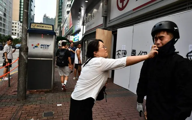 A woman tries to remove a facemask worn by a protesters after an anti-emergency law march from the Tsim Sha Tsui to Sham Shui Po areas of Hong Kong on October 12, 2019. Hong Kong protesters arrested for defying a new face mask ban appeared in court on October 7 following a violent weekend of unrest which saw bloody clashes with police and widespread vandalism that crippled the city's train network. (Photo by Anthony Wallace/AFP Photo)