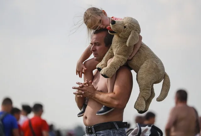 A girl holds a toy dog sitting on the shoulders of her father during the MAKS-2019 International Aviation and Space Salon in Zhukovsky outside Moscow, Russia,  01 September 2019. (Photo by Sergei Ilnitsky/EPA/EFE)