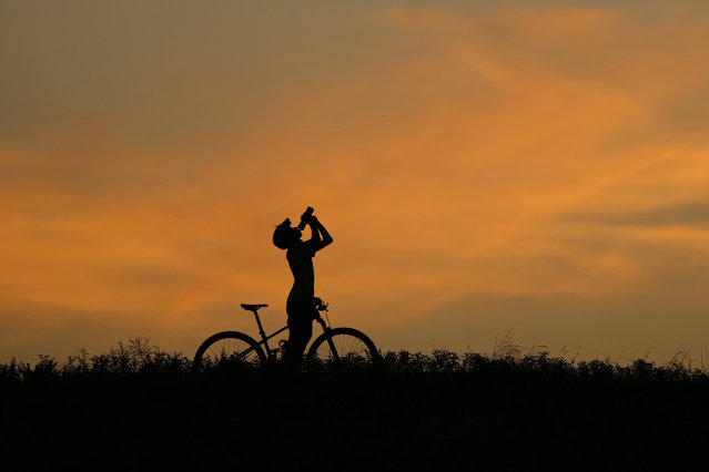 A cyclist takes a water break at dusk in San Antonio, Monday, July 1, 2024. South Texas began the month of July with triple digit temperatures. (Photo by Eric Gay/AP Photo)