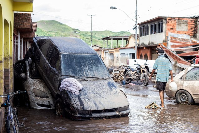 A man walks near damaged vehicles after devastating floods swept through the town after Hurricane Beryl passed off the Venezuelan coast, in Cumanacoa, Venezuela, on July 2, 2024. (Photo by Samir Aponte/Reuters)