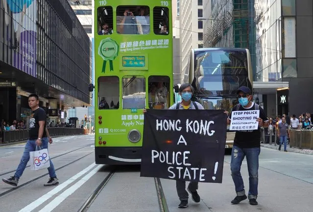 Protesters hold up a banner during a memorial flash mob to remember Chow Tsz-Lok in Hong Kong on Friday, November 8, 2019. Chow, a Hong Kong university student who fell off a parking garage after police fired tear gas during clashes with anti-government protesters died Friday, in a rare fatality after five months of unrest that intensified anger in the semi-autonomous Chinese territory. (Photo by Vincent Yu/AP Photo)