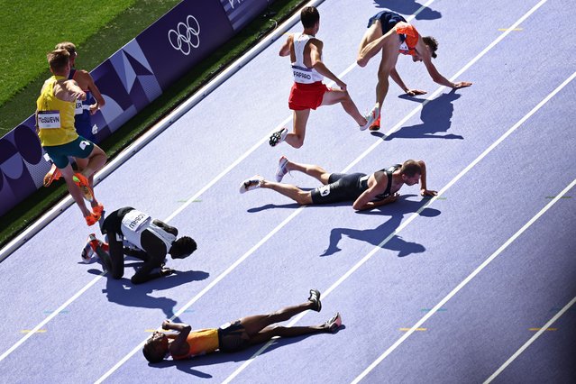 Spain's Thierry Ndikumwenayo, Refugee Team's Dominic Lokinyomo Lobalu, Britain's George Mills and Netherlands' Mike Foppen fall as they compete in the men's 5000m heat of the athletics event at the Paris 2024 Olympic Games at Stade de France in Saint-Denis, north of Paris, on August 7, 2024. (Photo by Anne-Christine Poujoulat/AFP Photo)