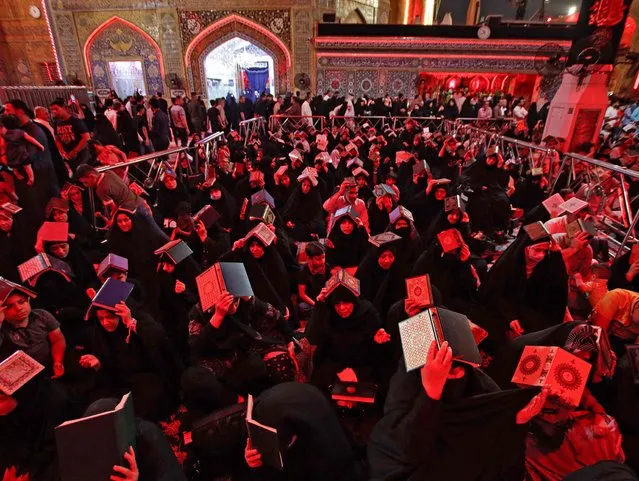 Worshippers place the Koran, Islam's holy book, on their heads during prayer rituals of Laylat al-Qadr (Night of Destiny) which marks the night in which the holy Koran was first revealed to the Prophet Mohammed, at the Imam Ali shrine in the holy Iraqi city of Najaf, late on April 20, 2022. (Photo by Ali Najafi/AFP Photo)